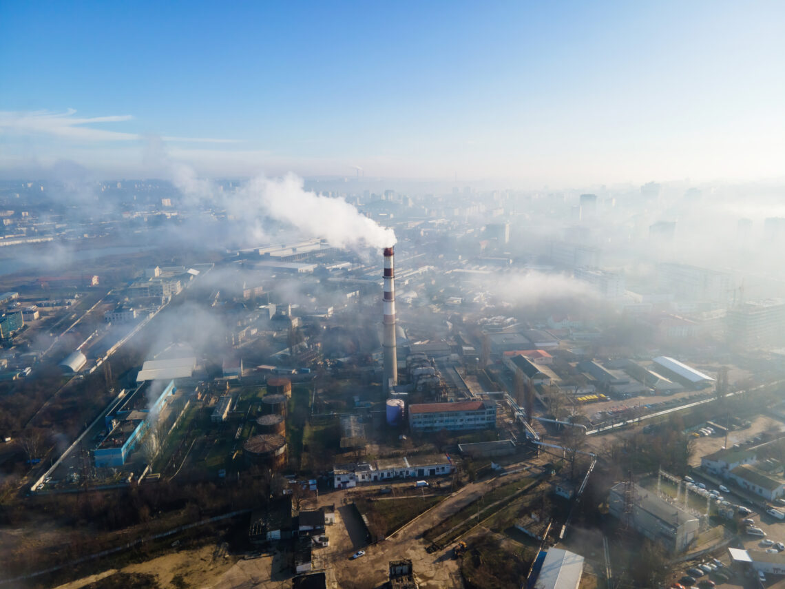 Aerial drone view of Chisinau. Thermal station with smoke coming out of the tube. Buildings and roads. Fog in the air. Moldova